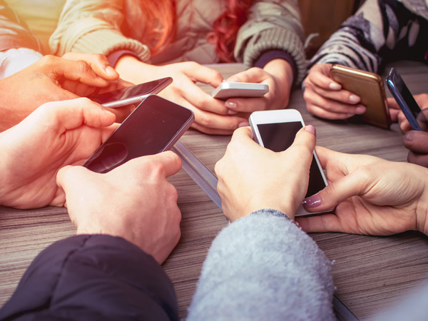 hands on smart phones - a group of friends using mobile phones sitting at the table